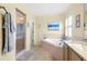 Bathroom with separate garden tub and glass shower, shuttered windows, and beach-themed decor at 29447 Schinnecock Hills Ln, San Antonio, FL 33576