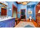 Bathroom with a dark wood vanity, tiled shower, blue walls, and a decorative rug at 3005 S Miller Rd, Valrico, FL 33596