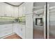 Bright kitchen with stainless steel refrigerator, white cabinets, gray countertop, and wood-look floor at 3213 W Cass St, Tampa, FL 33609