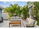 Inviting patio area featuring modern seating, a wooden coffee table, and a shade umbrella surrounded by tropical plants at 3213 W Cass St, Tampa, FL 33609