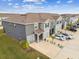 An aerial view of gray townhomes featuring private garages, ample parking, and manicured lawns at 33065 Major Oak Dr, Wesley Chapel, FL 33545