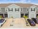 An aerial view of well-maintained gray townhomes with private garages, driveways, and manicured landscaping at 33065 Major Oak Dr, Wesley Chapel, FL 33545