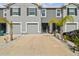 A contemporary two-story townhome features a gray stucco facade, attached garage, and a meticulously landscaped front yard at 33065 Major Oak Dr, Wesley Chapel, FL 33545