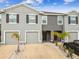 A modern gray townhome features an attached garage, well-kept landscaping, and a welcoming entrance at 33065 Major Oak Dr, Wesley Chapel, FL 33545