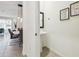 Modern powder room features a pedestal sink and decorative artwork, with dining area viewable through open doorway at 33065 Major Oak Dr, Wesley Chapel, FL 33545