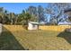 Fenced backyard with a grass lawn, a wooden shed, and a shade tree at 3412 71St N St, St Petersburg, FL 33710