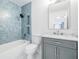 Beautifully designed bathroom with blue tile, shower and tub combo, modern vanity and large mirror at 3908 W Laurel St, Tampa, FL 33607