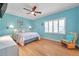 Turquoise bedroom featuring a ceiling fan, shutters, wood flooring, and wicker rocking chair at 399 150Th Ave # 101A, Madeira Beach, FL 33708