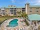 Overhead view of the pool area with travertine tile, lounge chairs, and a poolside pavilion at 399 150Th Ave # 101A, Madeira Beach, FL 33708