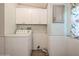 Bright laundry room with white cabinets, washer, shiplap, and decorative window treatment at 411 Dolphin S Dr, Oldsmar, FL 34677