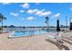 Outdoor pool with lounge chairs overlooking the waterfront on a sunny day with fluffy white clouds at 420 64Th Ave # 402, St Pete Beach, FL 33706