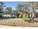 A lovely home with an American flag proudly displayed, framed by mature trees and shrubbery at 421 Wayfarer Ct, Tarpon Springs, FL 34689