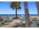 Inviting beach with serene ocean views, featuring two benches and shaded by a mature palm tree at 4812 Jasper Dr Dr # 101, New Port Richey, FL 34652