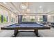 Bright game room features two billiards tables beneath modern lighting fixtures and has large windows at 4911 Sienna Isles Ave, Wimauma, FL 33598