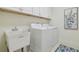 Functional laundry room with washer, dryer, sink, upper cabinets, and tile flooring at 4911 Sienna Isles Ave, Wimauma, FL 33598