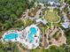 Aerial view of community center featuring clubhouse, pools, playground, and parking within a wooded area at 5134 Ballantrae Blvd, Land O Lakes, FL 34638