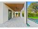 Expansive covered patio with stone pavers, ceiling fans, and views of the pool and yard at 531 Danube Ave, Tampa, FL 33606