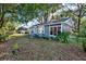 Quaint home exterior with charming details, a red door, and a landscaped yard surrounded by mature trees at 5518 11Th St, Zephyrhills, FL 33542