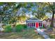 A cozy cottage-style home with a fenced yard and a striking red front door at 5518 11Th St, Zephyrhills, FL 33542