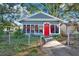 Charming home featuring a red front door, surrounded by windows and greenery at 5518 11Th St, Zephyrhills, FL 33542