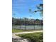 Community tennis court with fencing, lighting, and a view of mature trees and clear blue skies at 6800 20Th N Ave # 405, St Petersburg, FL 33710