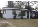Charming single-story home with white siding and a cozy front porch, enhanced by flags and small palm trees at 10554 116Th N Ave, Largo, FL 33773