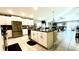 Open kitchen with white cabinetry, stainless steel appliances, and a large island overlooking the living area at 10854 Sage Canyon Dr, Riverview, FL 33578