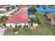 Aerial view showcases a red tile roof, screened pool, lush landscaping, and a serene lake backdrop at 1115 Signature Dr, Sun City Center, FL 33573