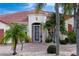 Close-up of the front entrance, framed by palm trees, a brick path, and a secure screen door at 1115 Signature Dr, Sun City Center, FL 33573