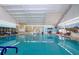 Large indoor pool features ample lighting, blue trim, and plenty of seating for residents to relax at 1115 Signature Dr, Sun City Center, FL 33573
