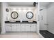 Bright bathroom featuring double sinks, modern fixtures, and a spacious walk-in shower with black pebble flooring at 1123 Hounds Run, Safety Harbor, FL 34695