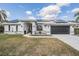 Charming home featuring solar panels, a dark garage door, and impeccable landscaping at 1123 Hounds Run, Safety Harbor, FL 34695