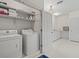 Bright laundry room featuring white washer and dryer with shelving and cabinets, providing ample storage space at 11806 Willow Point Way, Tampa, FL 33618