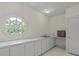 Charming laundry room boasts a unique round window and white cabinets, offering both style and functionality at 11806 Willow Point Way, Tampa, FL 33618