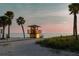 A lifeguard stand overlooks the sandy beach and calm ocean waters, framed by tall palm trees at sunset at 1312 Gulf Rd, Tarpon Springs, FL 34689