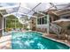 Screened pool with a covered patio that includes chairs and an umbrella, surrounded by lush landscaping at 1312 Gulf Rd, Tarpon Springs, FL 34689