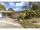 Charming yellow single-story home featuring a blue front door, attached garage, and well-kept landscaping at 1431 54Th Ne Ave, St Petersburg, FL 33703