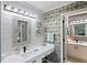 Well-lit bathroom with double vanities, decorative mirrors, and stylish wallpaper at 1801 E Lake Rd # 9G, Palm Harbor, FL 34685