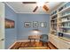 Stylish blue office with custom built-in bookshelves, hardwood floors, and decor at 304 Silver Falls Dr, Apollo Beach, FL 33572