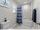 Bright bathroom with a tub-shower combo, tiled walls, and a blue-and-white striped shower curtain at 3133 King Fern Dr, Wimauma, FL 33598