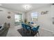 Dining room with a glass-top table, blue velvet chairs, and sliding glass doors to an outdoor patio at 3133 King Fern Dr, Wimauma, FL 33598