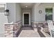 Front porch featuring a beautiful front door, stone accents, a 'Welcome' mat, and a rocking chair at 3133 King Fern Dr, Wimauma, FL 33598