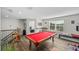 Bright game room features a red pool table, seating, and entertainment area with a window for natural light at 3133 King Fern Dr, Wimauma, FL 33598