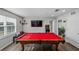 Game room with a red pool table, hardwood floors, and a large television for entertainment at 3133 King Fern Dr, Wimauma, FL 33598