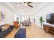 Open-concept living space featuring a blue sectional, modern entertainment center, and dining area flowing into the kitchen at 33277 Rosewood Bark Way, Wesley Chapel, FL 33545