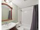 Bathroom with a white tiled shower with curtain and wood framed mirror at 4037 Chesswood Dr, Holiday, FL 34691