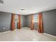 Bedroom featuring tile flooring and two bright windows with orange curtains at 4037 Chesswood Dr, Holiday, FL 34691