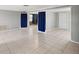 Large living room with tile flooring, doors covered by blue curtains and neutral walls at 4037 Chesswood Dr, Holiday, FL 34691