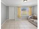 Cozy living room featuring neutral tones, a large window with vibrant curtains, and stylish tile flooring at 4037 Chesswood Dr, Holiday, FL 34691