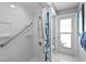 Bright, white tiled shower with grab bars, a shower chair, hand held shower head, and frosted glass door at 4464 46Th S Ave, St Petersburg, FL 33711